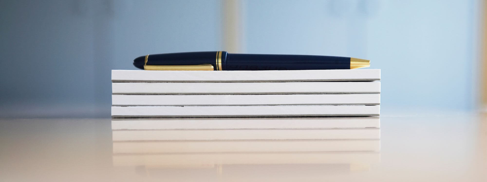 stack of white scratch pads with a black pen on top