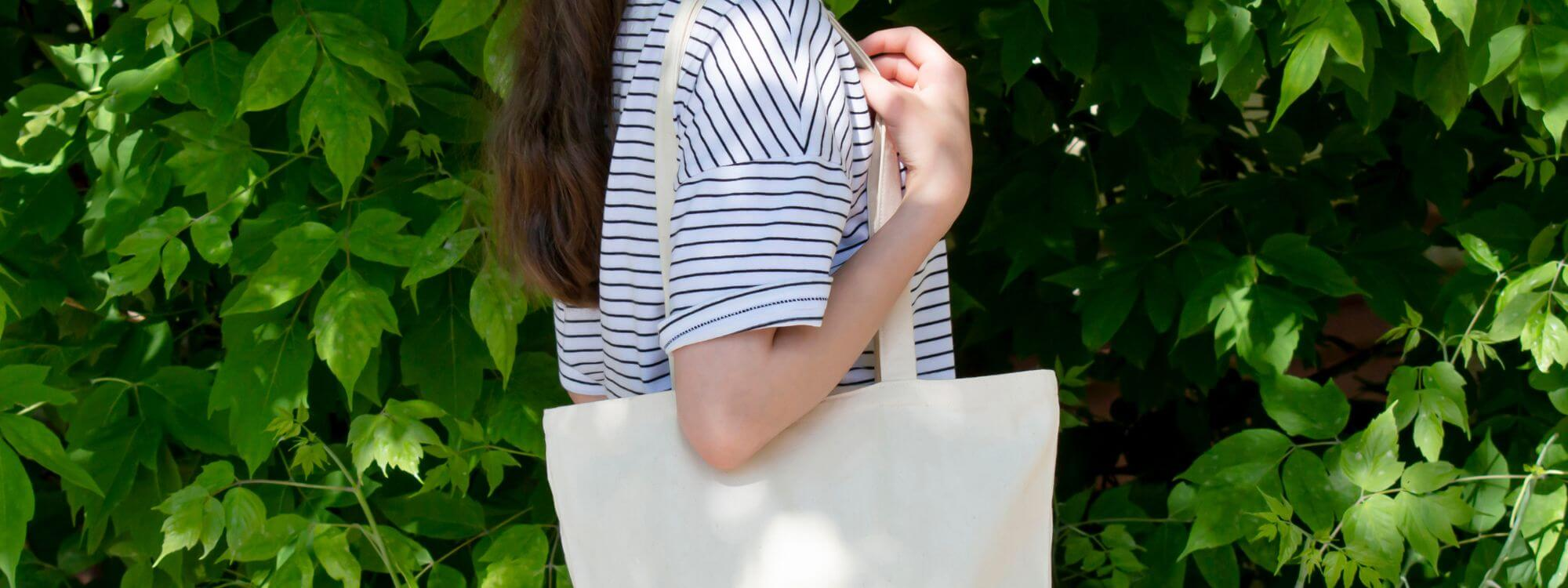 woman walking outside with a cotton tote bag over one shoulder